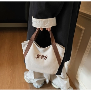 Detail of high-density canvas tote bag with brown XOG embroidery and handles