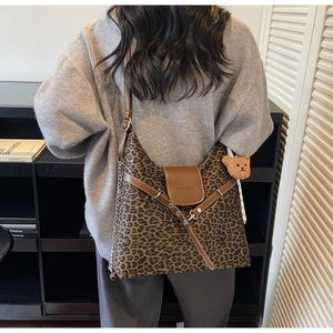 Detail of leopard print tote bag featuring metallic chains and brown bear plush charm