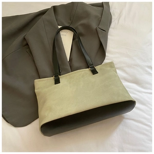 Detail of green canvas tote bag with black leather base showing fabric texture and stitching