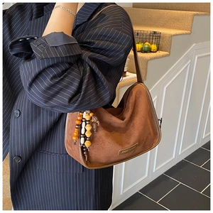 Detail of brown suede tote bag with colorful vintage beaded charm on a model