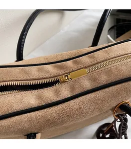 Detail of beige suede handbag featuring premium gold metal zipper and black leather trim