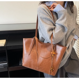 Brown vintage leather tote bag with unique wooden bead tassel detail and large capacity