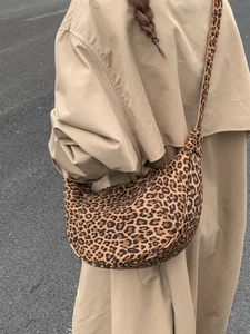 Chic leopard print half-moon crossbody bag shown in a stylish outdoor street style view