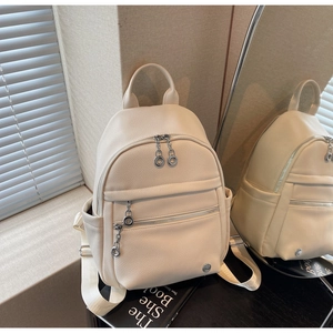 Detail of cream white pebbled leather backpack with ring pull zippers and side pockets