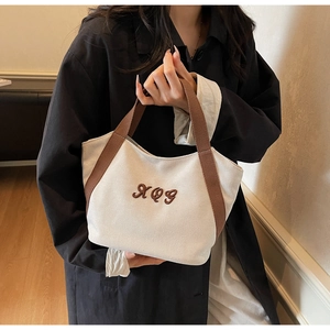 Detailed close-up of the artistic XQG brown embroidery on high-quality off-white canvas bag