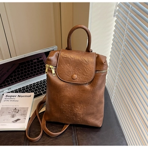 Détail d'un sac à dos en cuir marron vintage avec lettrage embossé à la lumière du jour