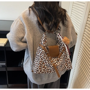Detail of leopard print tote bag with brown leather trim and cute plush bear charm decoration