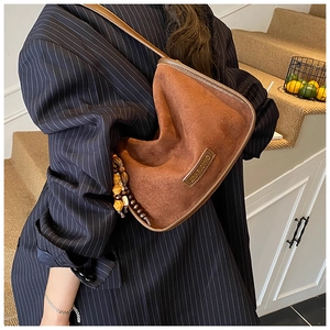 Detail of brown suede crossbody bag with vintage wooden beads and logo embossing