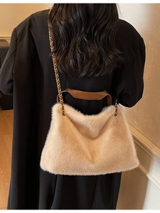 Furry beige tote bag with brown leather handles and gold chain strap shown on a model