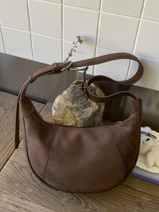 Minimalist dark brown suede hobo bag with a half-moon shape and adjustable strap
