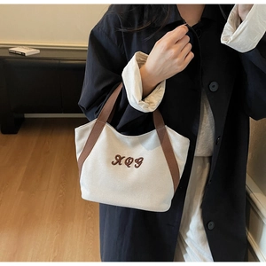 Detail of canvas tote bag with brown XQY embroidery and matching handles