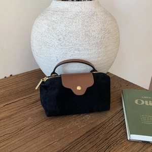 Close-up of suede texture and brown leather flap with gold snap button detail