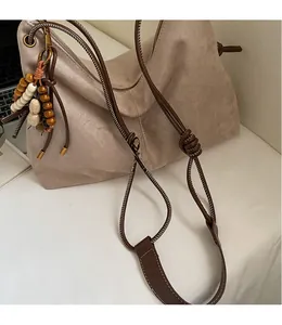 Detail der hellbraunen Wildleder-Tragetasche mit Knotengurt und Vintage-Perlenanhänger