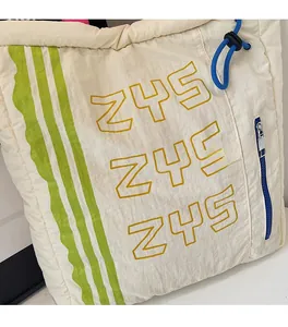 Detail of off-white canvas tote with neon green stripes and blue drawstring accents