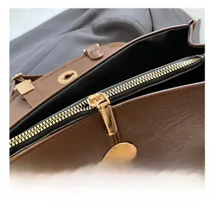 Detail of vintage brown leather handbag featuring high-quality gold metal zipper and hardware