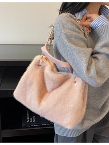 Pink plush tote bag with gold chain strap shown on model for a stylish winter look