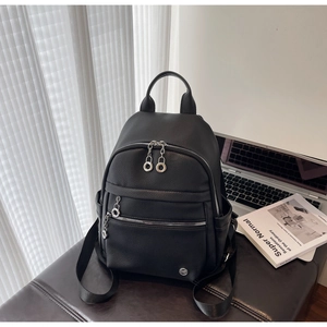 Close-up of black lychee texture leather backpack with multi-zipper and silver round pulls