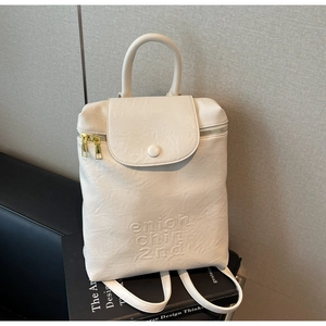 Détail du sac à dos beige en similicuir avec texture grainée et fermeture dorée