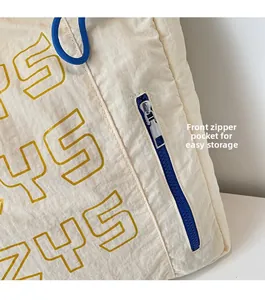 Detail of beige canvas tote featuring a blue zipper pocket and yellow 245 print