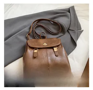 Detail view of a vintage dark brown leather backpack with golden twist lock on a gray blazer