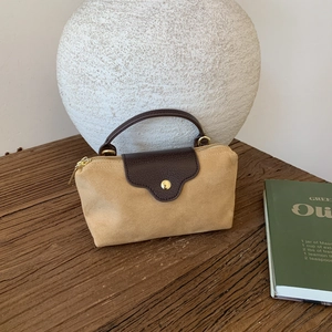 Detailed view of suede and leather handbag texture on a rustic wooden table