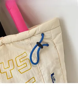 Detail of quilted tote bag featuring a blue elastic drawstring and pink handle