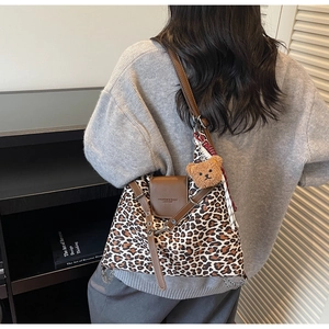 Detail of leopard print tote bag with brown leather strap and plush bear charm