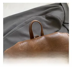 Detail of the brown leather top handle and gold circular metal twist lock on a vintage bag
