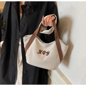 Detailed view of beige canvas tote bag with brown XOG embroidery and sturdy handles