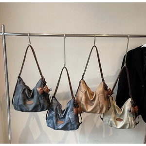 Detail view of large tote bags in grey, denim blue, camel, and cream with bow charms