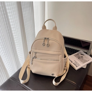 Detail of cream backpack with pebble grain leather texture on a brown bench