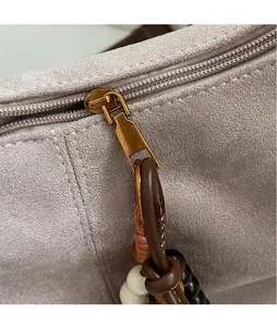 Detail eines glatten Bronze-Reißverschlusses und Quasten-Anhängers an der Tasche