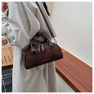 Detalle de bolso cilíndrico de gamuza marrón con logo PANTOOR plateado y asas de cuero