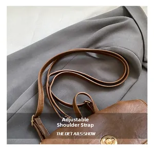 Detail of adjustable leather shoulder strap and gold hardware on brown vintage handbag