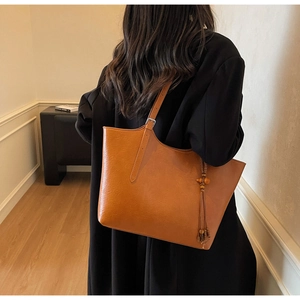 Brown vintage tote bag detail with bohemian tassel charm and adjustable strap
