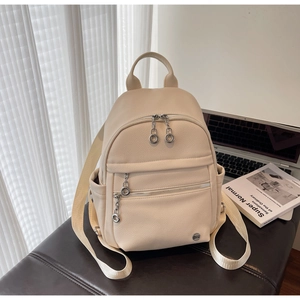 Detailed macro view of beige pebble grain leather backpack with silver chain zipper