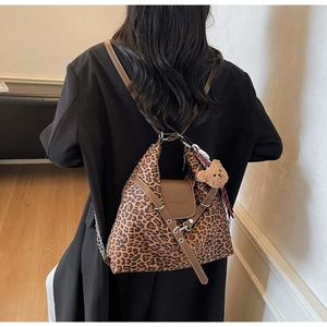Close-up of leopard print tote featuring leather flap, metal clasp, and plush bear charm