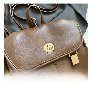 Close-up of vintage brown leather backpack with gold twist-lock hardware detail