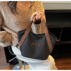 Detail of grey canvas tote bag with brown handles and XQG embroidery for daily use