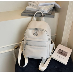 Detail of white litchi pattern PU leather backpack with silver zippers and webbing straps