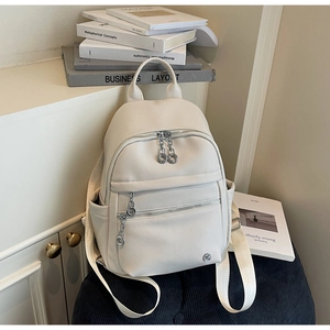 Detail of beige pebble leather mini backpack with silver ring zippers and side pockets