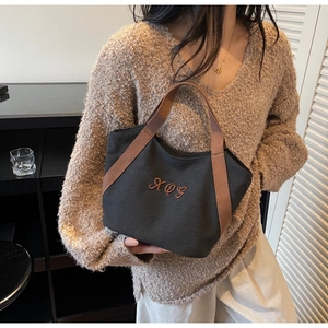 Close-up of black canvas tote bag with brown KQG embroidery and durable strap detail