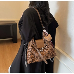 Detail of leopard print tote bag with brown leather flap and bear charm accessory