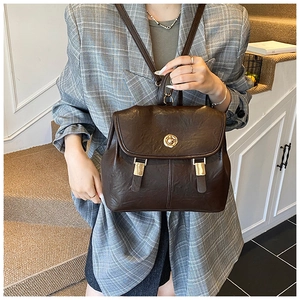 Detail of dark brown leather backpack with golden twist lock and decorative straps