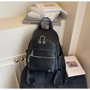 Detail of black pebbled leather backpack showing silver zippers and multi-pocket design