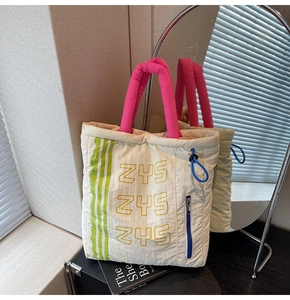 Detailed shot of a quilted tote bag with pink straps and green stripes on a display table