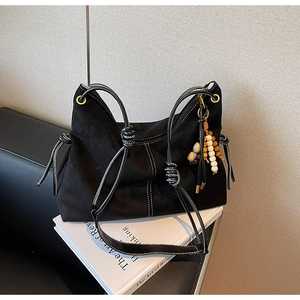 Detail der schwarzen Wildledertasche mit Kontrastnähten und Perlenanhänger-Dekor