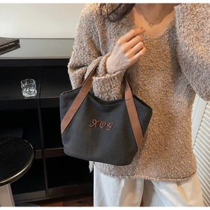 Detail of canvas tote bag with contrast brown straps and XQG embroidery detail