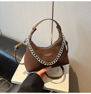 Détail du sac demi-lune en daim marron avec chaîne argentée et bandoulière en cuir