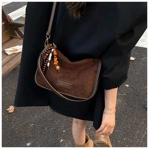 Detail of dark brown suede shoulder bag with beaded fringe tassel in outdoor setting